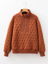 A warm rust-colored geometric quilted half zipped sweatshirt with triangular stitching and ribbed cuffs machine wash safe