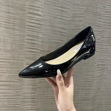 Woman’s hand holding black patent leather point toe flats loafer