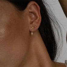 Woman wearing copper bow stud earrings with pearl drop on ear