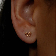 Gold copper bow stud earring with pearl drop on earlobe