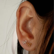 Close-up of ear with gold and silver copper bow stud earrings and pearl drops