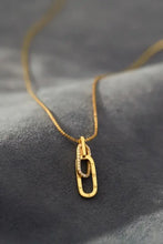 Gold chain necklace with interlocking oval pendants, one with clear stones, multiple chain lengths