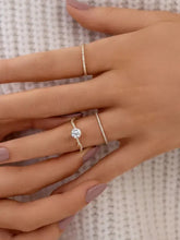 Hand with pink nails wearing three slender 925 sterling silver inlaid zircon rings with diamonds