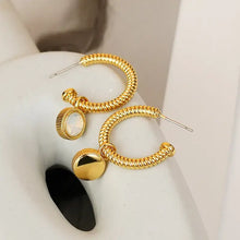 Gold hoop earrings with textured gold, polished ball drop, and cat’s eye stone charms