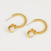 Gold hoop earrings with white cat’s eye stone charms