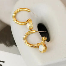 Gold hoop earrings with white cat’s eye stone charms