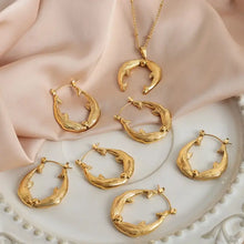 Gold horseshoe jewelry set with leafy hoop earrings and dolphin necklace