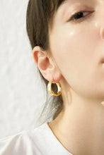 Golden brass huggie earring on person’s ear