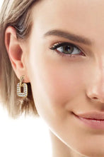 Brincos pendentes elegantes com moissanite em quilates no rosto de uma mulher