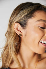 Gold rhinestone eye stud earring on woman’s earlobe with evil eye design