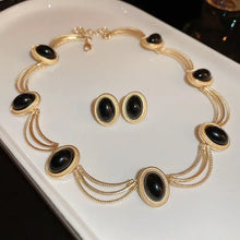 Gold-tone oval gemstone necklace and earrings set with black cabochons