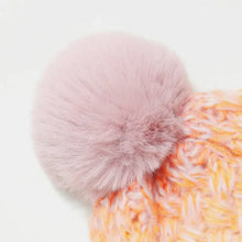 Gradient knit hat with pink faux fur pompom on orange yellow knit fabric