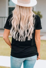 Person in graphic cuffed sleeve round neck tee with blonde wavy hair