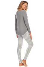 A soft gray graphic round neck top with relaxed fit paired with matching light gray striped leggings set