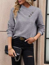 Gray textured sweater with asymmetrical neck and buttons, black jeans