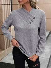 Gray textured button-up sweatshirt with asymmetrical neck, black distressed jeans, white sneakers