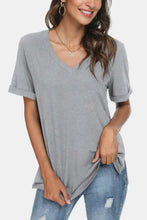 Woman in light gray V-neck short sleeve t-shirt with rolled cuffs and distressed jeans