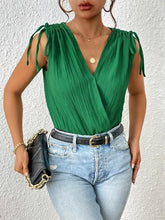 Woman in green and black tie shoulder bodysuit with jeans
