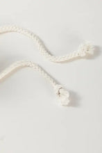 White braided cord bracelet with knot closure on green and white checkered hoodie