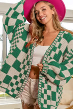 Green and white checkered open long sleeve cardigan with fringe trim and pink hat