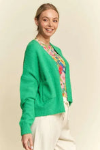 Green drop shoulder cardigan with relaxed fit, floral blouse, white pants