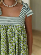 Green and white striped floral summer dress with ruffled details and pearl necklace