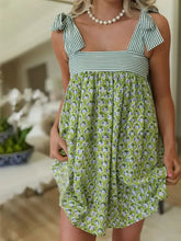 Green floral summer dress with ruffled hem, square neckline, and pearl necklace