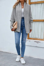Grey long sleeve textured cardigan with white turtleneck and distressed jeans
