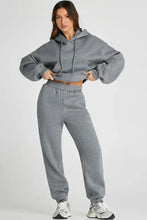 Grey oversized hoodie with drawstring, pockets, and full length joggers paired with white sneakers