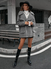 Grey faux fur oversized teddy bear coat with black accents, pockets, and chain shoulder detail