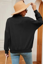 Woman in half zip dropped shoulder sweatshirt, jeans, tan hat, sunglasses