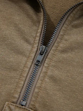 A dark gray metal zipper with a matte finish on an olive green mineral wash baggy half zip kangaroo pocket hoodie