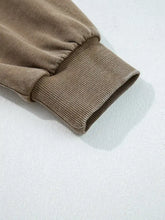 The tapered ribbed cuff of a beige half zip mineral wash baggy hoodie showing the mineral wash finish texture