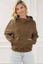 Woman in brown long sleeve hoodie with quarter-zip and jeans