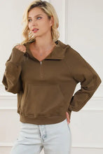 Woman in brown long sleeve hoodie with kangaroo pocket and light wash jeans