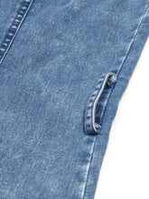 A close-up of faded blue denim fabric with stitching and frayed pocket loop on a halter neck button-front denim dress
