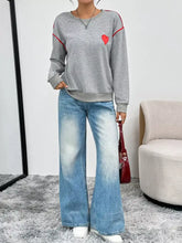 Gray heart embroidered round neck sweatshirt with red trim and patch made of slightly stretchy material