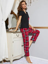 Red and black plaid pajama pants with subtle white grid pattern paired with heart graphic v-neck top with sleeve length detail