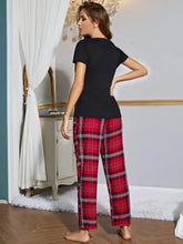 Red and black plaid pajama pants with white accents paired with a heart graphic v-neck top featuring long sleeve length