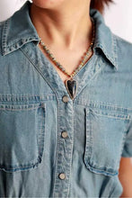 Woman in light blue denim shirt wearing heart-shaped labradorite natural stone pendant beaded necklace