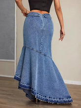 A medium-wash denim maxi skirt with a mermaid silhouette, asymmetrical slit, frayed hem, and classic button closure