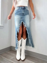 A faded blue high-waist denim skirt with raw hem asymmetry and a distressed frayed split down the front