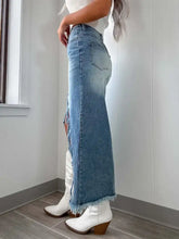 High-waist raw hem asymmetry denim skirt in faded blue wash with distressed ripped side panels and frayed hem