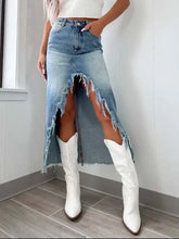 High-waist denim skirt with raw hem asymmetry featuring a distressed frayed hemline and side slit design