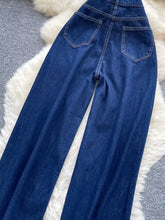 Dark blue denim high waist wide leg jeans showing the back side with two pockets and a high waist design
