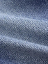 Medium-wash blue denim fabric with classic twill weave and subtle fading of high waist wide leg jeans