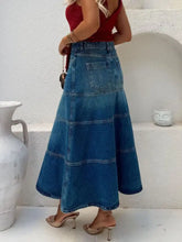 High-waisted denim skirt in blue featuring tiered flared silhouette with classic patch pockets machine wash safe