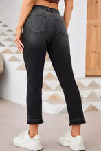 Black high-waisted distressed hem straight leg jeans with a faded wash and frayed hems in cropped style