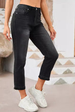 Black high-waisted distressed hem straight leg jeans with faded wash and frayed hems in high-rise cropped style