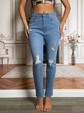 High-waisted light blue denim distressed jeans with ripped knees and frayed hems for a trendy casual look